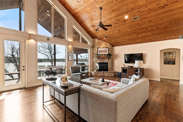 living room with visible vents, high vaulted ceiling, wood finished floors, a stone fireplace, and wood ceiling