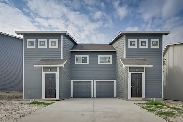 view of front facade featuring concrete driveway, an attached garage, and roof with shingles