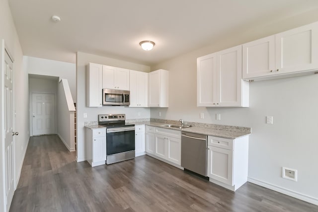 kitchen featuring a sink, light stone counters, appliances with stainless steel finishes, white cabinets, and dark wood-style flooring