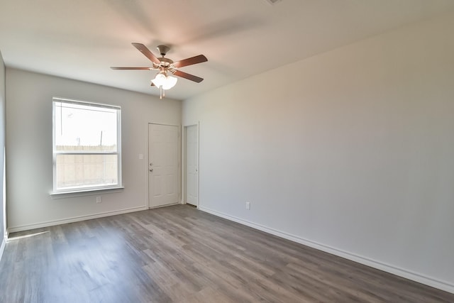 empty room featuring dark wood finished floors, baseboards, and a ceiling fan