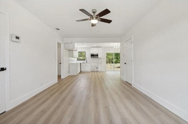 unfurnished living room with light wood-style flooring, baseboards, and ceiling fan