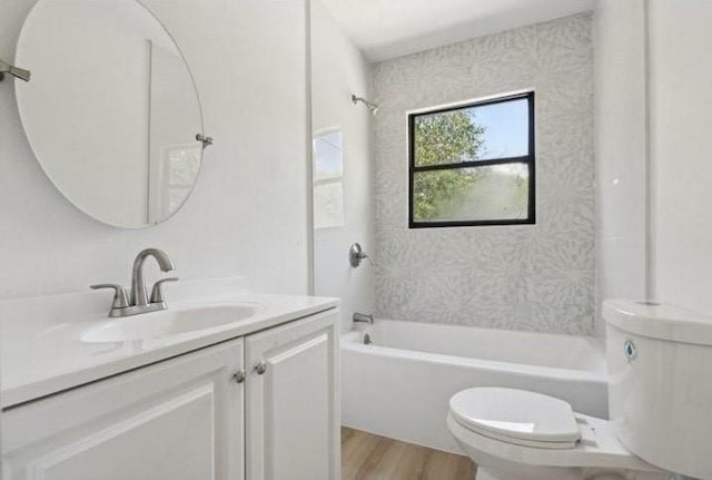 bathroom with washtub / shower combination, toilet, vanity, and wood finished floors