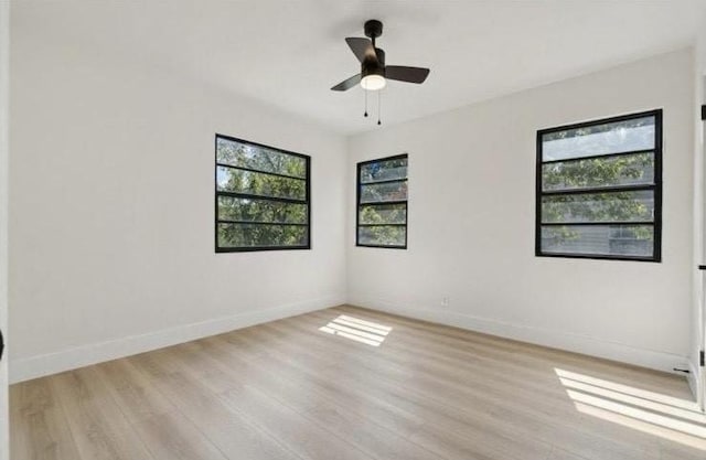 unfurnished room featuring a wealth of natural light, light wood-type flooring, and baseboards