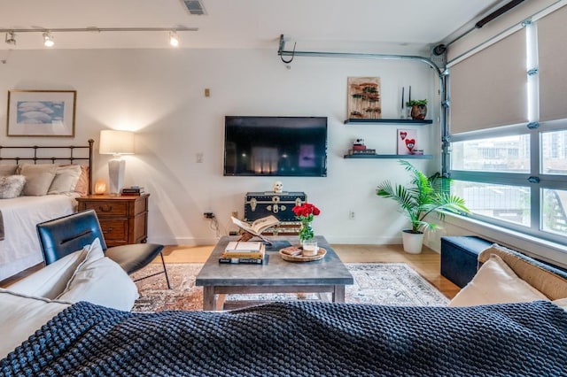 bedroom featuring track lighting, baseboards, a garage, and wood finished floors