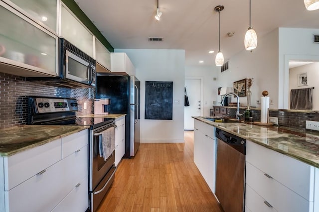 kitchen featuring light wood-style flooring, a sink, white cabinets, appliances with stainless steel finishes, and modern cabinets