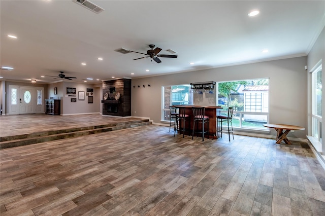 1809 Faulkner Dr, Rowlett, TX 75088 - living area featuring visible vents, crown molding, wood finished floors, a fireplace, and a bar