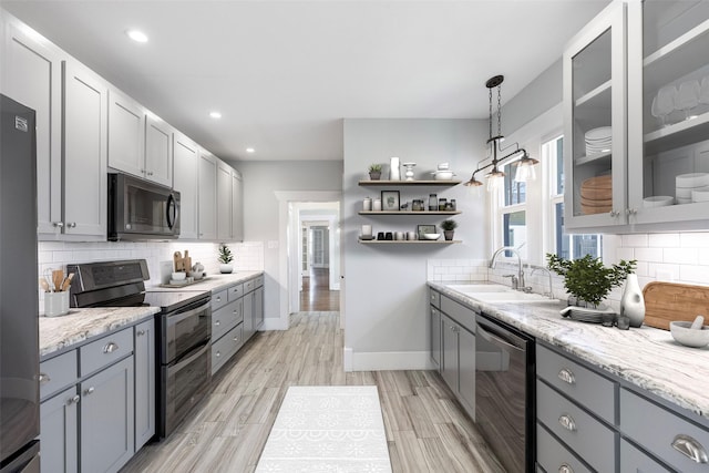 kitchen with light wood finished floors, gray cabinets, black appliances, and a sink