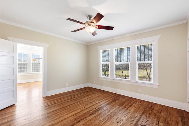 empty room with baseboards, wood finished floors, ornamental molding, and a ceiling fan