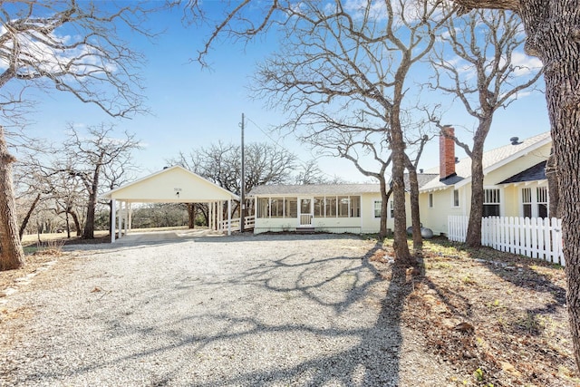 view of front of home with a sunroom, fence, driveway, and a chimney