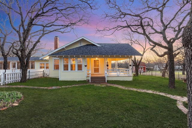 view of front of home with a front lawn, a porch, fence, a shingled roof, and a chimney