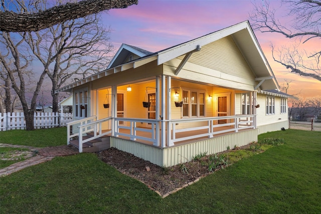 view of front of home featuring a lawn, covered porch, and fence