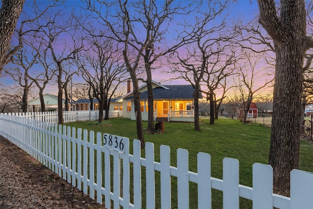 view of front of home with a fenced front yard, a lawn, and covered porch