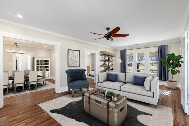 living room with ceiling fan with notable chandelier, wood finished floors, recessed lighting, crown molding, and baseboards