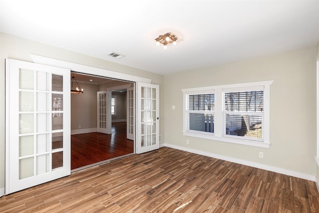 unfurnished room featuring visible vents, french doors, baseboards, and wood finished floors