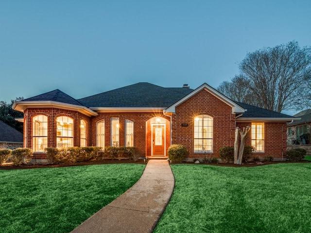 ranch-style home featuring brick siding, a chimney, a front lawn, and a shingled roof