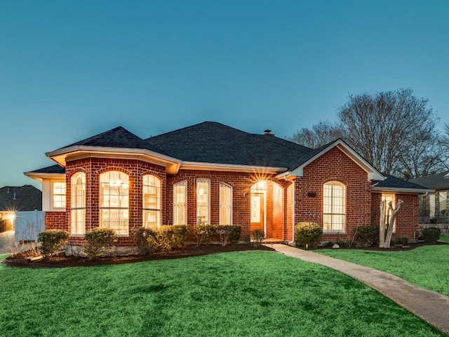 ranch-style house featuring brick siding, a front yard, and a shingled roof