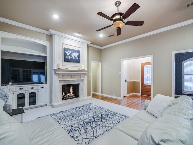 living area featuring visible vents, wood finished floors, ornamental molding, and a fireplace