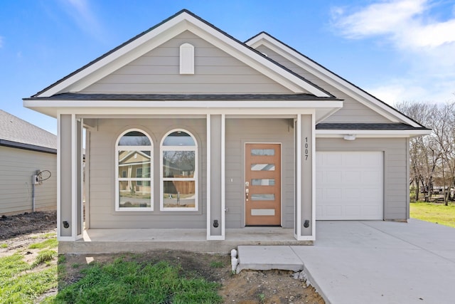 view of front of house with a garage, roof with shingles, covered porch, and concrete driveway