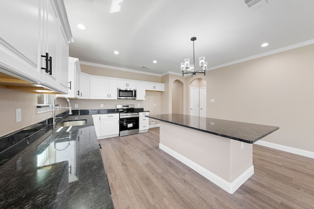 kitchen featuring visible vents, light wood-style flooring, arched walkways, a sink, and stainless steel appliances