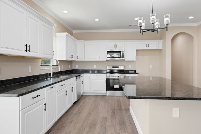 kitchen featuring a sink, stainless steel appliances, light wood-style floors, white cabinets, and crown molding