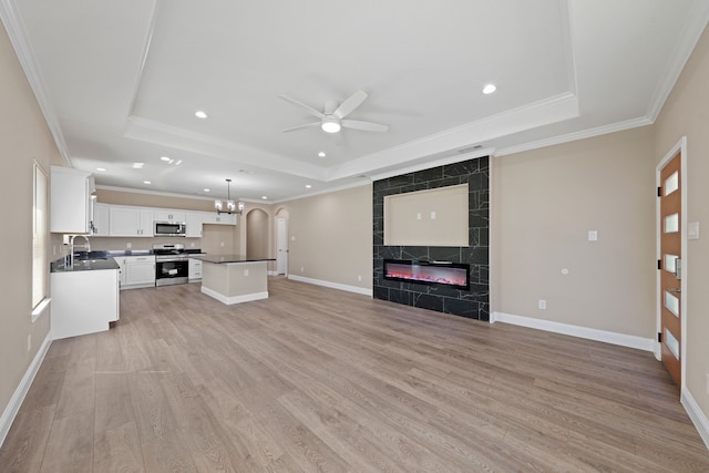 kitchen with stainless steel appliances, a raised ceiling, dark countertops, and open floor plan