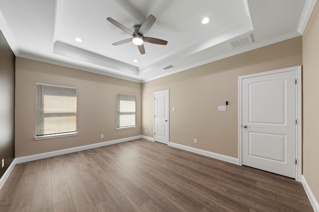 spare room with visible vents, baseboards, a tray ceiling, ornamental molding, and wood finished floors