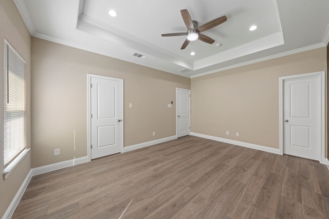 unfurnished bedroom with a tray ceiling, multiple windows, and visible vents