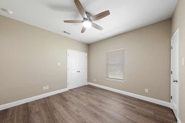 unfurnished bedroom with a ceiling fan, wood finished floors, visible vents, baseboards, and a closet