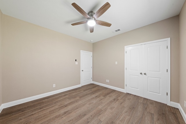 unfurnished bedroom featuring visible vents, a ceiling fan, wood finished floors, a closet, and baseboards