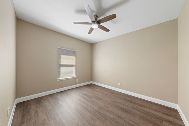 unfurnished room featuring dark wood-type flooring, a ceiling fan, and baseboards