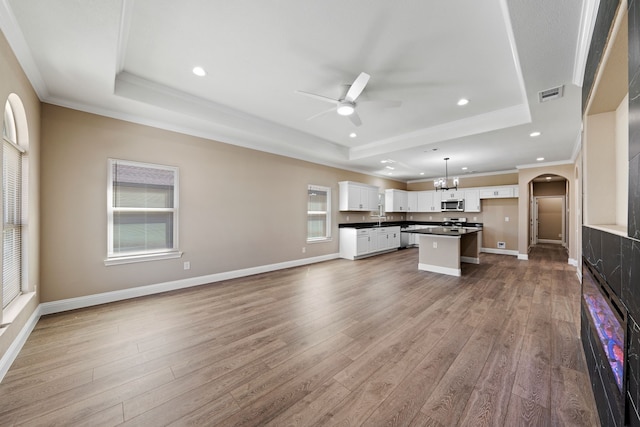 kitchen with stainless steel microwave, a raised ceiling, dark countertops, and visible vents