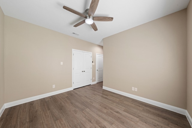 unfurnished room featuring a ceiling fan, visible vents, wood finished floors, and baseboards