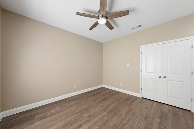 unfurnished bedroom with wood finished floors, visible vents, baseboards, ceiling fan, and a closet