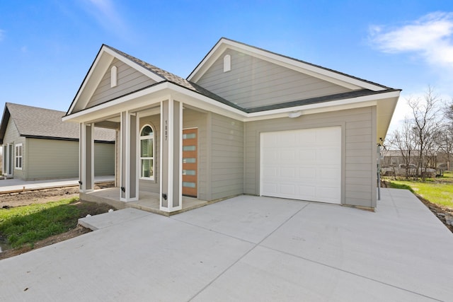 view of front of house with roof with shingles, a porch, concrete driveway, and an attached garage