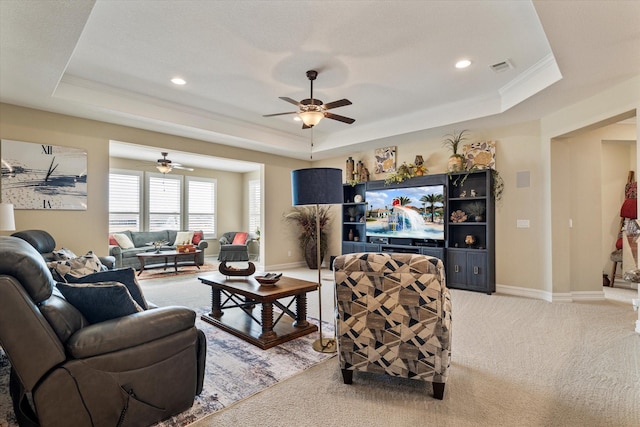 living room with a tray ceiling, light carpet, and baseboards