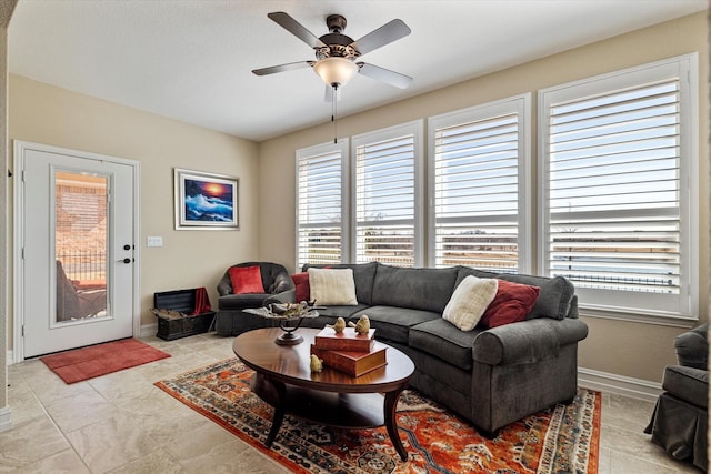 living area with baseboards and a ceiling fan