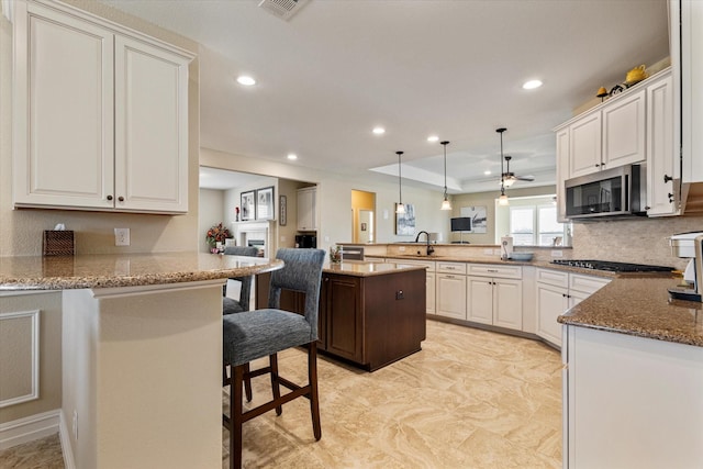 kitchen with appliances with stainless steel finishes, stone countertops, a peninsula, and a sink