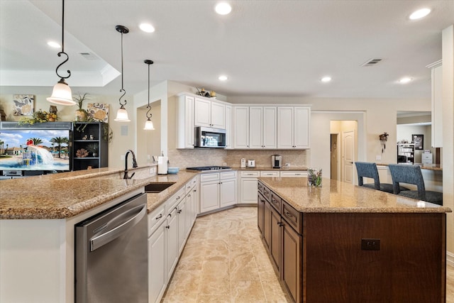 kitchen featuring light stone countertops, visible vents, appliances with stainless steel finishes, white cabinetry, and backsplash