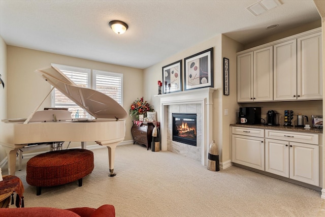 interior space with visible vents, baseboards, light colored carpet, and a tile fireplace