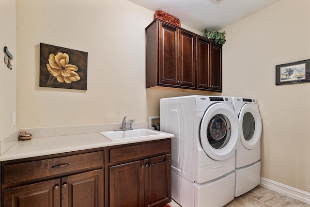 laundry room featuring washer and dryer, cabinet space, baseboards, and a sink