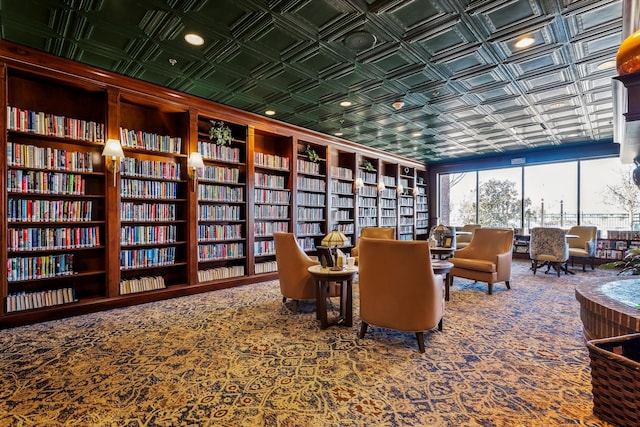 sitting room with built in features, an ornate ceiling, carpet flooring, and bookshelves