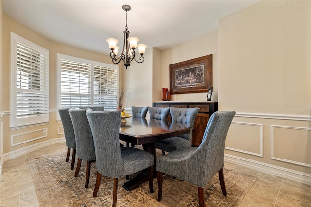 dining space featuring a decorative wall, a wainscoted wall, and a chandelier