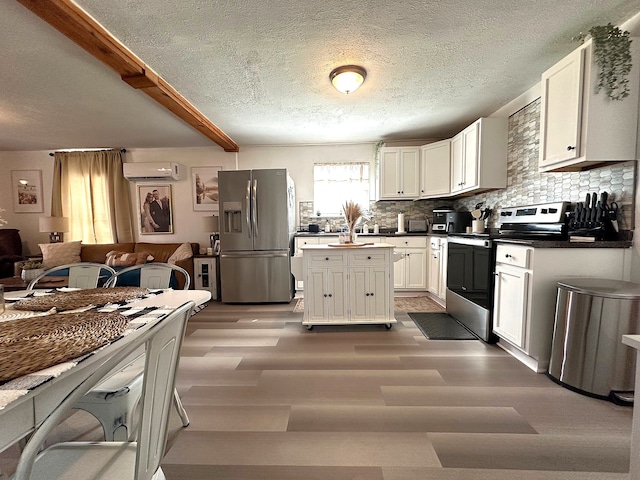 kitchen featuring a wall mounted air conditioner, decorative backsplash, appliances with stainless steel finishes, and white cabinetry