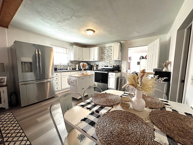 kitchen with backsplash, a kitchen island, appliances with stainless steel finishes, wood finished floors, and white cabinetry