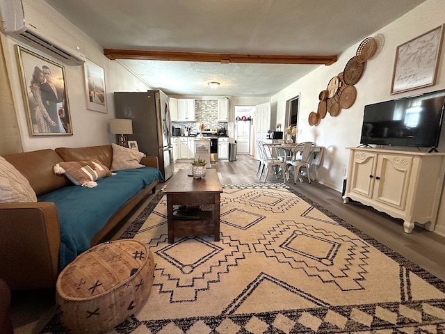 living room featuring beam ceiling, a wall unit AC, and wood finished floors