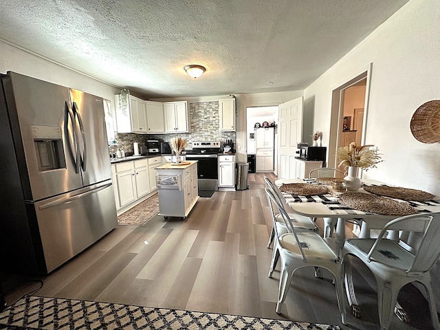 kitchen featuring dark wood-style floors, a center island, white cabinetry, stainless steel appliances, and decorative backsplash