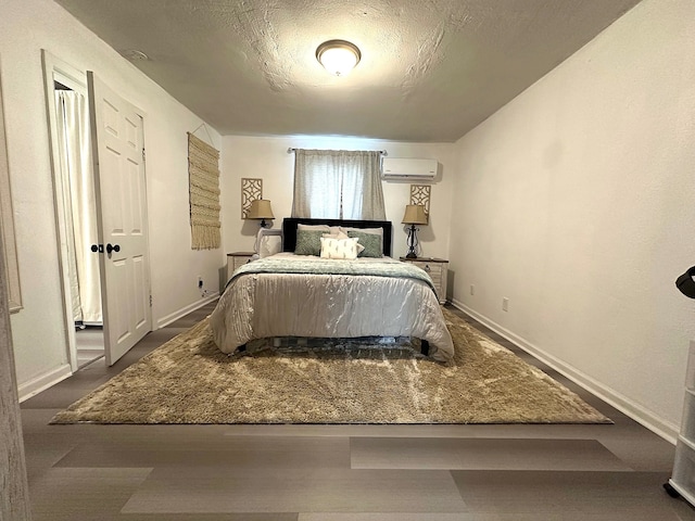 bedroom featuring baseboards, a textured ceiling, and a wall mounted AC