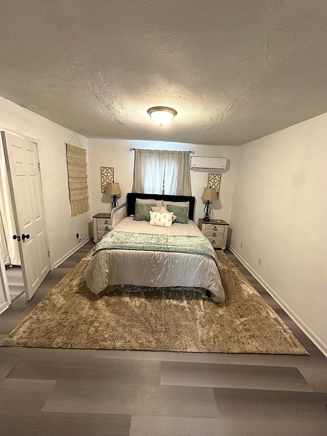 bedroom featuring baseboards, a textured ceiling, and a wall unit AC