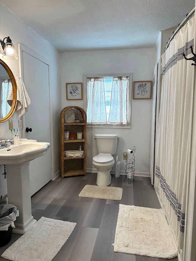 bathroom with baseboards, toilet, and a textured ceiling