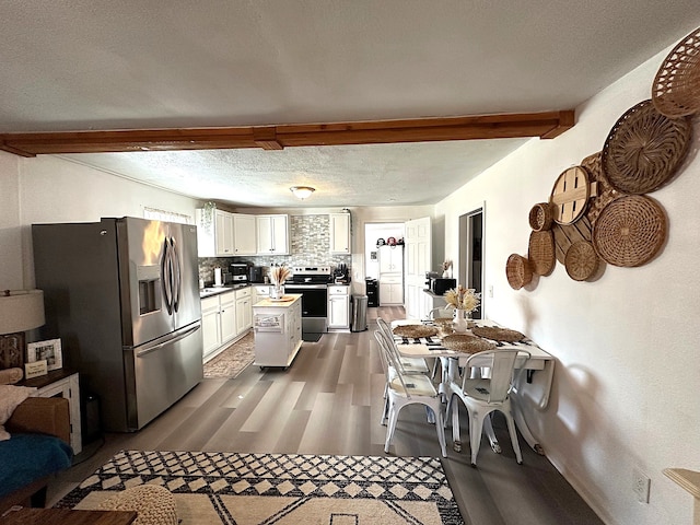 kitchen with stainless steel appliances, dark wood-type flooring, a textured ceiling, white cabinetry, and backsplash